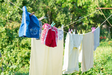 Clean laundry drying on line outside green background