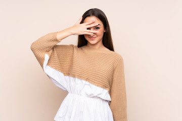 Young caucasian woman isolated on beige background covering eyes by hands and smiling