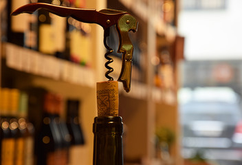 Wine bottles on wooden shelf in wine store and corks with corkscrew