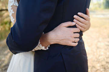 Happy wedding couple walking on garden, copy space. Close up of young bride and groom hugging outdoors
