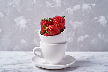 Ripe organic strawberries in white ceramic bowl on gray background, copy space. Healthy food concept, still life
