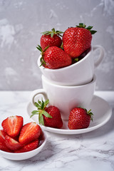 Ripe organic strawberries in white ceramic bowl on gray background, copy space. Healthy food concept, still life