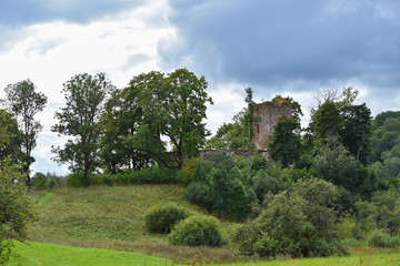 Beautiful green landscape with ruins of old stone church on hill with trees around it