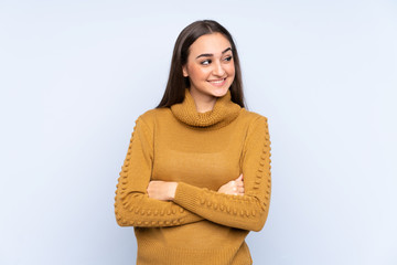 Young caucasian woman isolated on blue background looking up while smiling