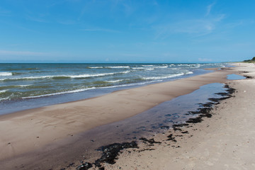 Steep sand shore beach with clouds and blue sky
