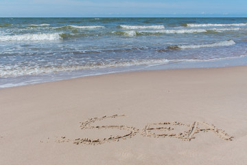 Text ''sea'' written in beach sand