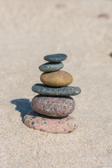 Fototapeta na wymiar Stack of stones on sand beach near sea. Zen garden. Pebble tower.