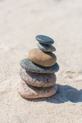 Fototapeta na wymiar Stack of stones on sand beach near sea. Zen garden. Pebble tower.