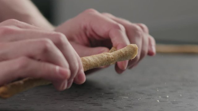 Slow motion man breaking grissini on concrete countertop