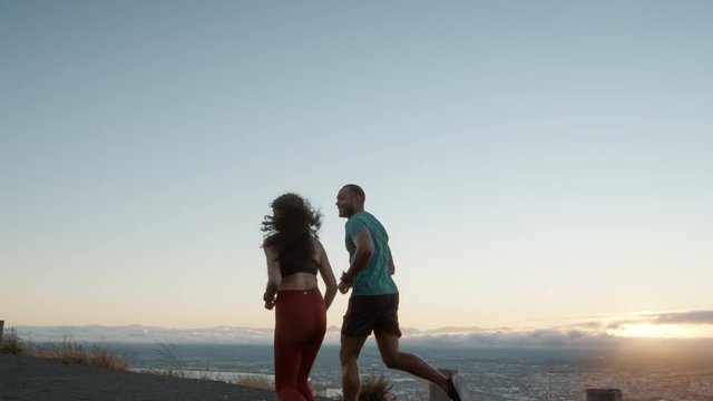 Healthy young couple jogging together in the morning. Happy young man and woman running on a hillside road.