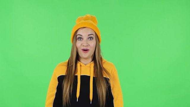 Portrait of modern girl in yellow hat confused saying oops and shrugging. Green screen