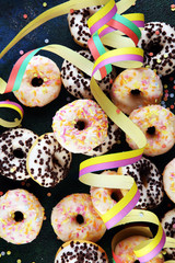 holiday donuts with colorful party streamers and confetti on rustic background