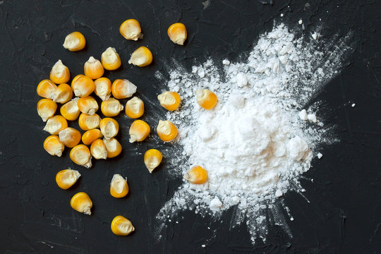 Corn starch with yellow grains on a black background, top view. Corn white starch and yellow kernels on the table. Starch and corn grains on a black background, top view. Copy space