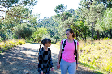 Mom and daughter on a walk in nature, woman has dressed sports top girl has black striped shirt, mountain nature and forest road in around Benahavis Andalucia Spain