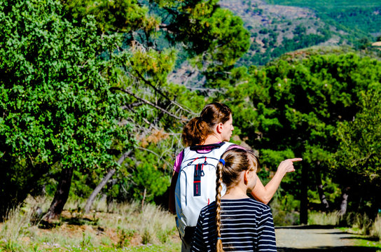 Mom and daughter on a walk in nature, woman has dressed sports top girl has black striped shirt, mountain nature and forest road in around Benahavis Andalucia Spain