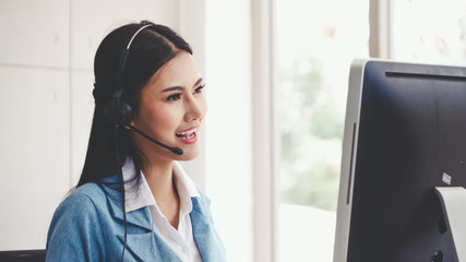 Customer support agent or call center with headset works on desktop computer while supporting the customer on phone call. Operator service business representative concept.