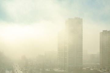 Built new high-rise building in dense morning fog with penetrating rays of the sun.