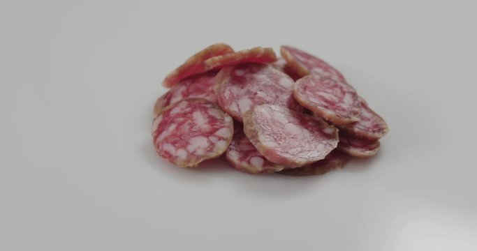 Fuet sausage slices rotating on white background