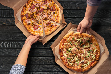 Overhead view of hands taking pizza from cardboard box - Powered by Adobe