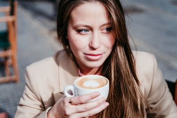 portrait of beautiful caucasian woman on a terrace drinking coffee. urban and lifestyle concept
