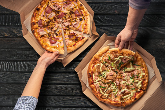 Overhead view of hands taking pizza from cardboard box