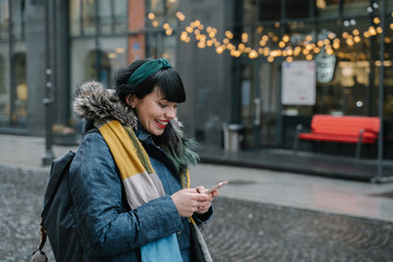 Stylish woman using smartphone in the street