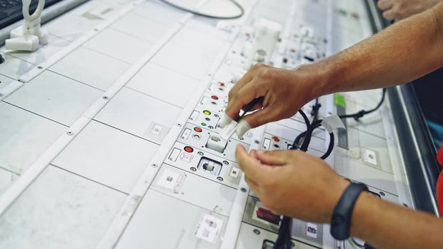 Hands employee during manufacture the wiring. Process of manufacturing the wiring harnesses for vehicles
