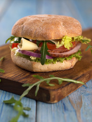 hamburger with vegetables, meat and cheese on a wooden board.