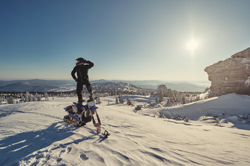 Snowbike rider in mountain valley. Modify dirt bike with snow splashes and trail. Snowmobile sport riding, winter sunny day