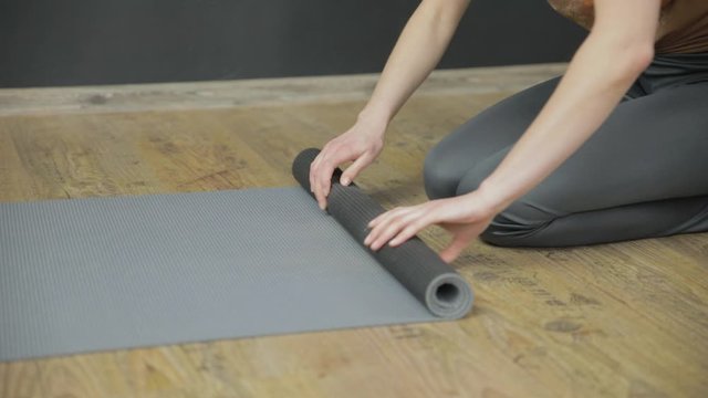 Close-up of a woman rolling her yoga mat