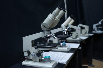 Microscopes set on the worktable of the school lab, black background