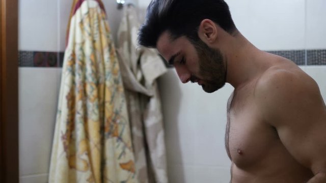 Attractive muscular young man dressing in bathroom
