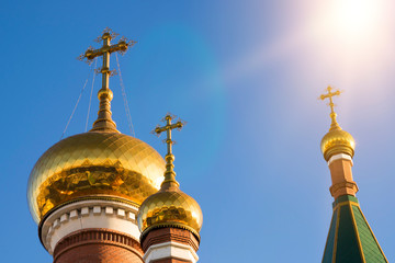 Fototapeta na wymiar Three domes of the Orthodox Church against the blue sky. Religious building .