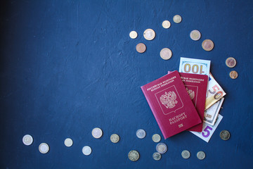 A pair of passports with dollar and Euro bills embedded in them, on a dark, dark blue background.