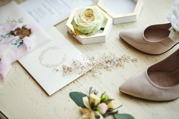 bridal accessories such as shoes, bouquet , ring and  invitation cards lie on a table