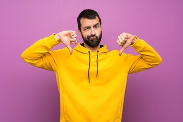 Handsome man with yellow sweatshirt showing thumb down