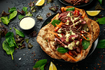Grilled and sliced beef steak on garlic and coriander naan bread with carrot and spinach salad drizzled with home made mayonnaise sauce