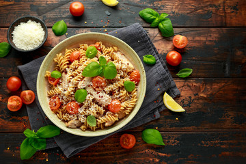 Healthy Chicken, fusilli pasta with tomatoes, basil and parmesan cheese. on wooden table. - obrazy, fototapety, plakaty