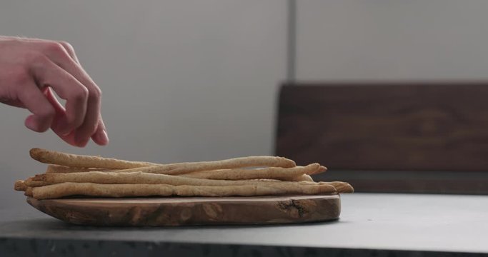 Slow motion man hand take homemade grissini from olive board