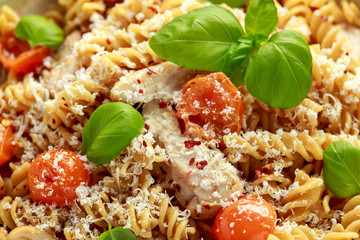 Healthy Chicken, fusilli pasta with tomatoes, basil and parmesan cheese. on wooden table.