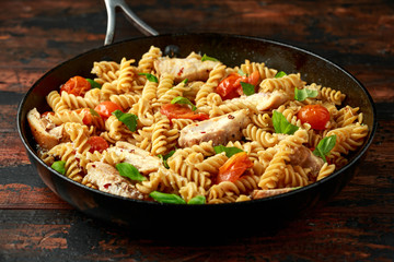Healthy Chicken, fusilli pasta with tomatoes, basil and parmesan cheese in iron pan.