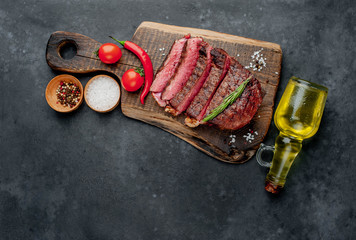 Beef steak on a cutting board with spices and tomatoes on a stone background with copy space for your text.