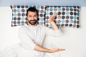 Man in bed in top view holding copyspace to insert an ad