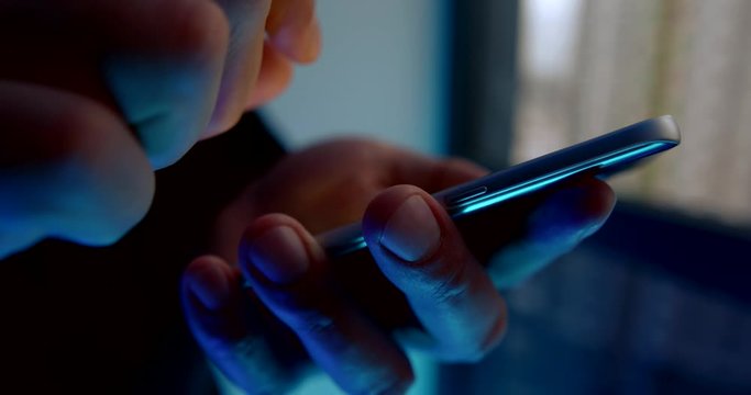 close-up of men's hands holding a mobile phone while running their fingers over the touch screen.