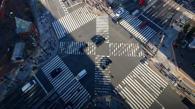 Timelapse of aerial view over a traffic cars and a crowd of pedestrian crossing street. Elevated view over an asian people locals and tourists walking in busiest road intersection. -Dan