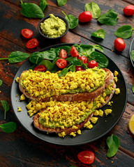 Scrambled Tofu crispy Toast with guacamole and spinach, tomato salad. Vegan vegetarian, plant based food