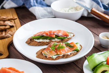 healthy sandwiches toats with salmon avocado cucumber  cream cheese dill on plate