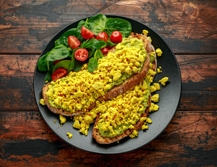 Scrambled Tofu crispy Toast with guacamole and spinach, tomato salad. Vegan vegetarian, plant based food