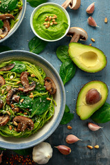 Vegan garlic mushroom pasta with spinach and avocado pesto drizzled with sesame seeds and roasted...