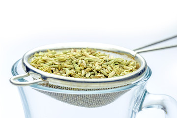 fennel seeds loose inside sieve ready to be brewed for healthy drink on white background